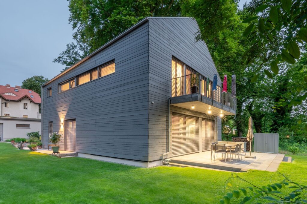 House with grey Gendai cladding in front of trees and with lawn